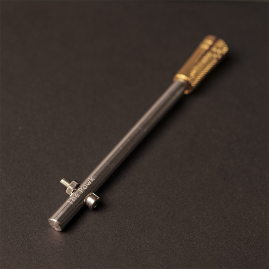The Powk handpoke tattoo tool with brass grip and stainless steel, aluminium needle bar on dark background