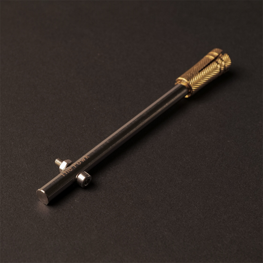 The Powk handpoke tattoo tool with gold brass grip and stainless steel, aluminium needle bar on dark background