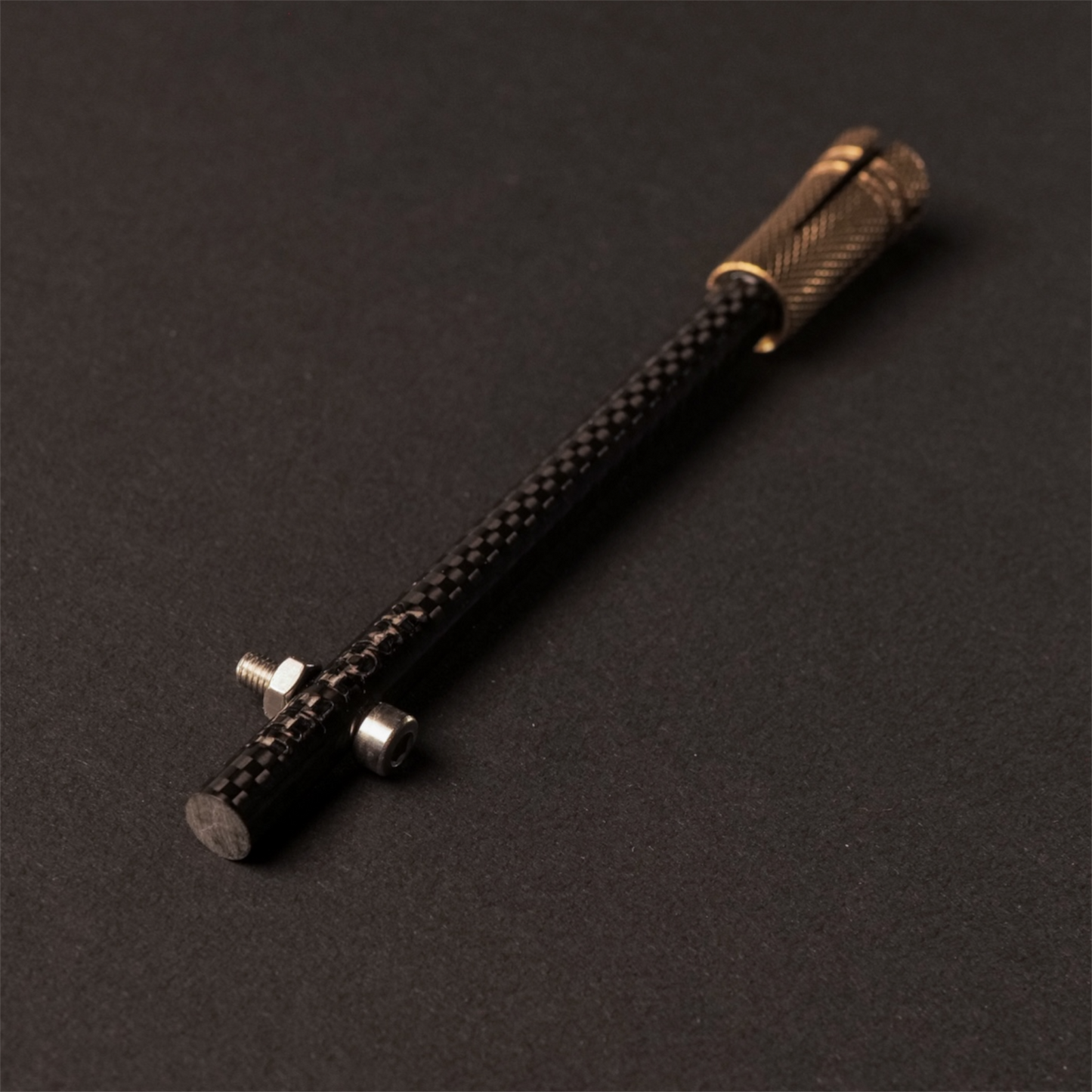 The Powk handpoke tattoo tool with gold brass grip and Carbon Fiber  needle bar on dark background