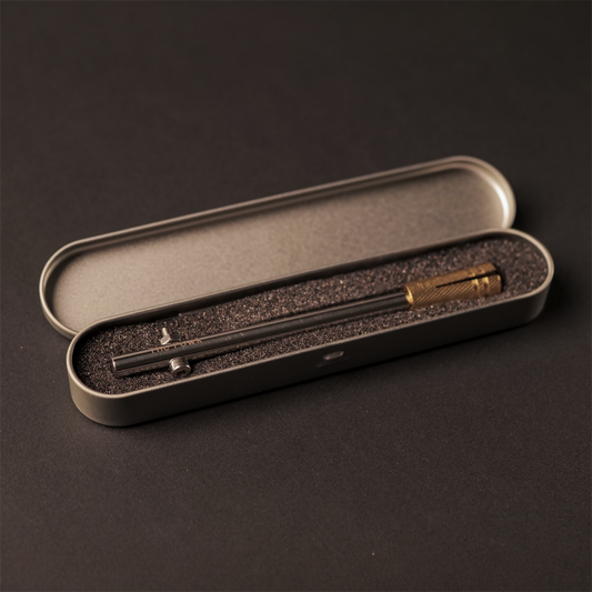 The Powk handpoke tattoo tool with gold brass grip and stainless steel, aluminium needle bar on dark background