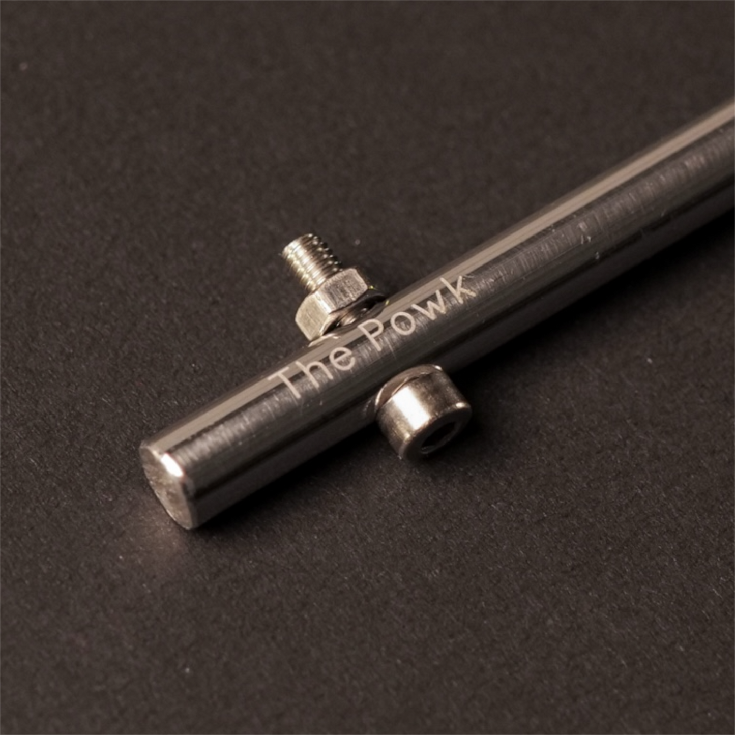 The Powk handpoke tattoo tool with gold brass grip and stainless steel, aluminium needle bar on dark background