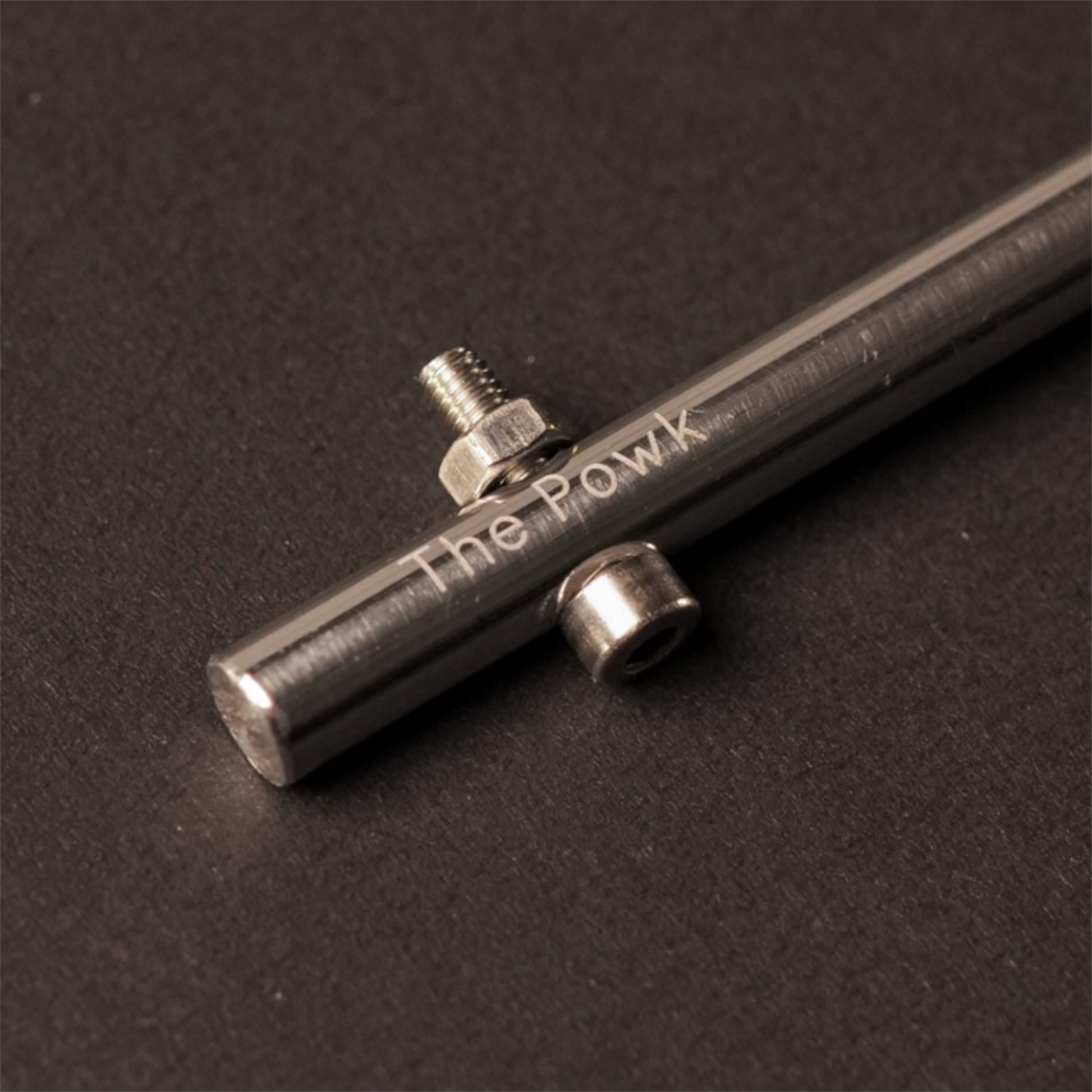 The Powk handpoke tattoo tool with gold brass grip and stainless steel, aluminium needle bar on dark background